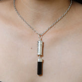 Black Tourmaline sterling silver capsule pendant worn on a model, showing polished silver locket and raw black crystal drop.