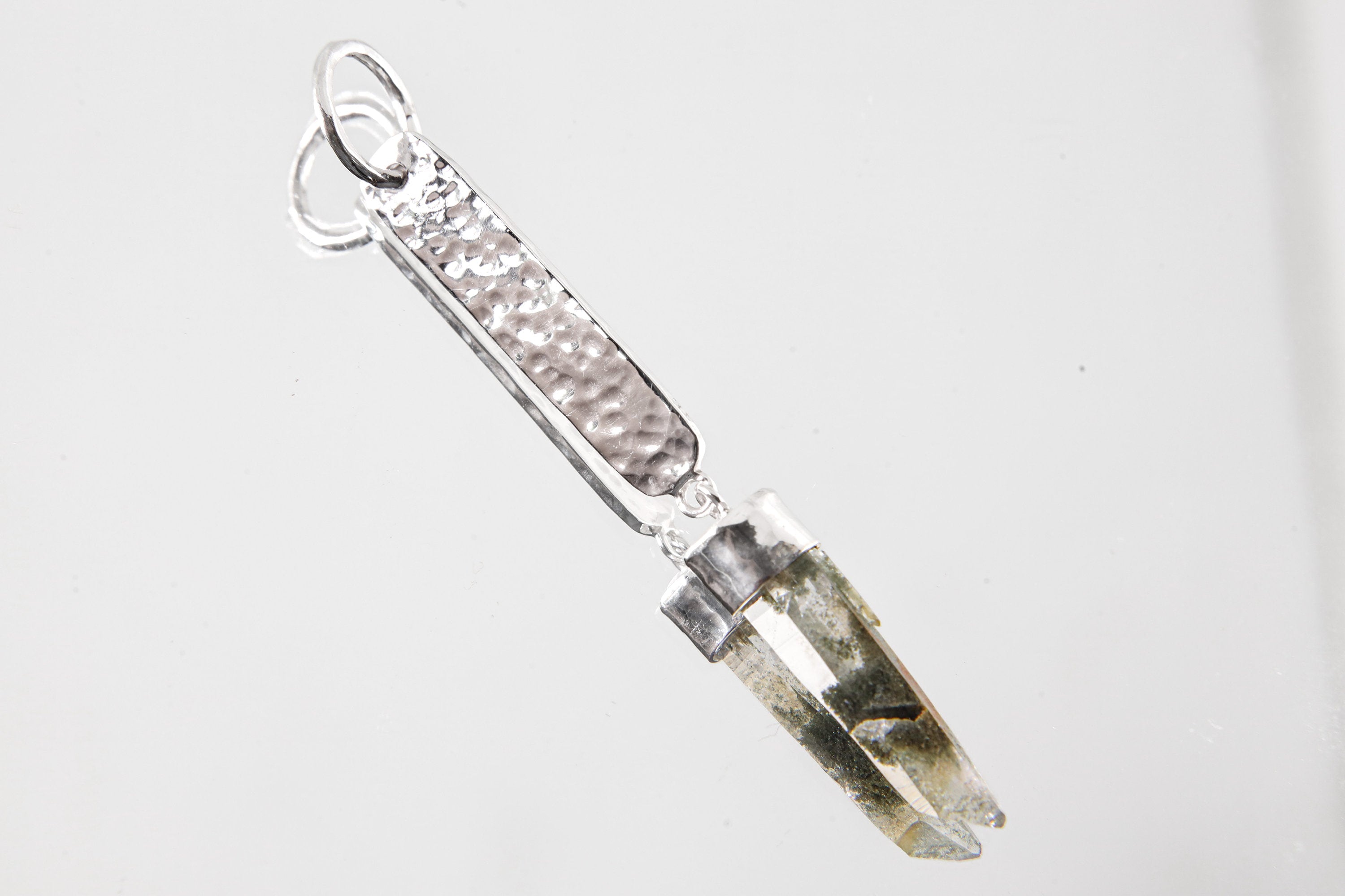 Alpine Light Himalayan Quartz pendant shown on white background with hammered 925 sterling silver and crystal point.