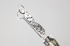 Close-up of hammered sterling silver pendant showing bright texture, round bail, and handmade silver detail.
