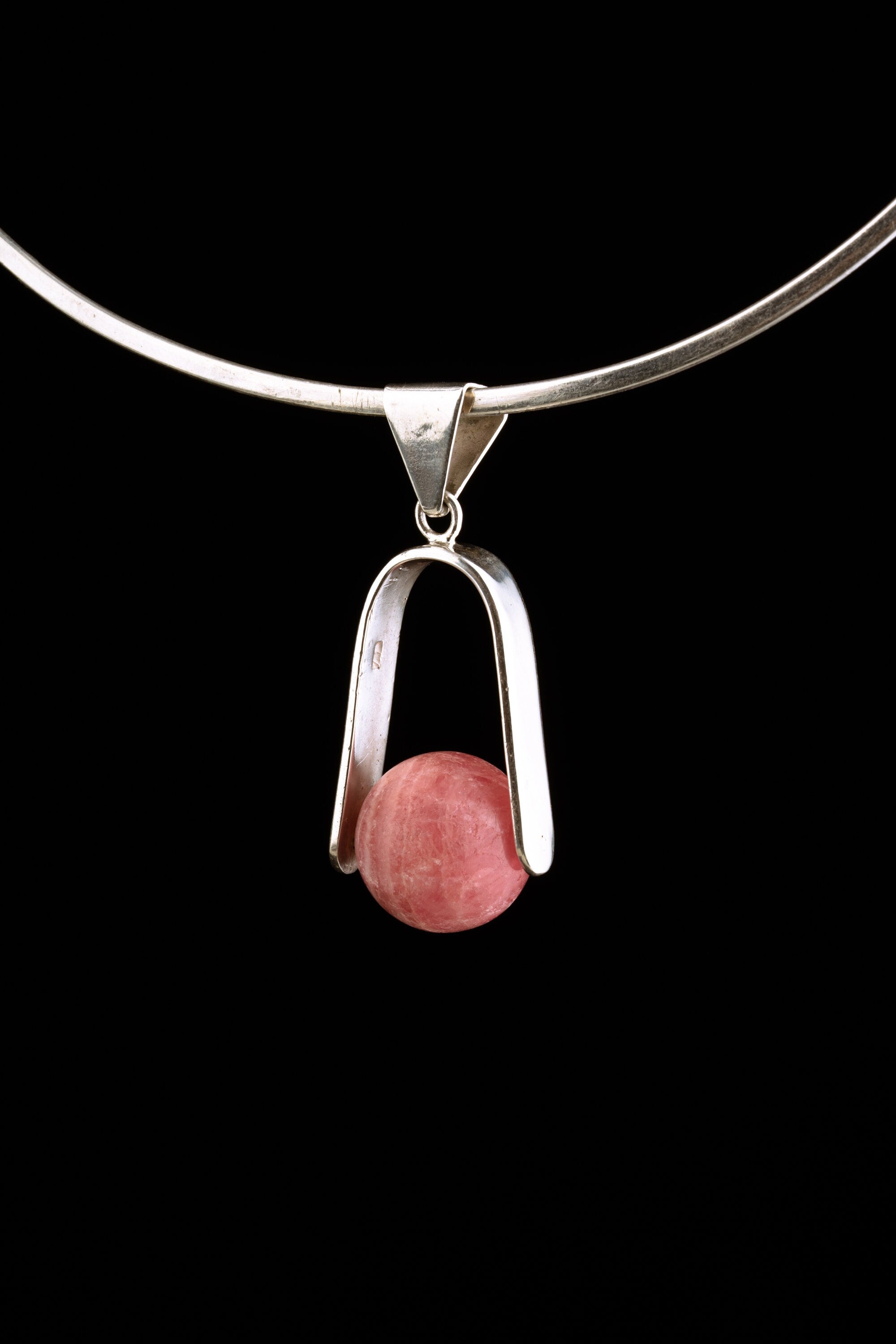 Rhodochrosite spinning pendant displayed on a choker as a polished sterling silver Heart Chakra necklace.