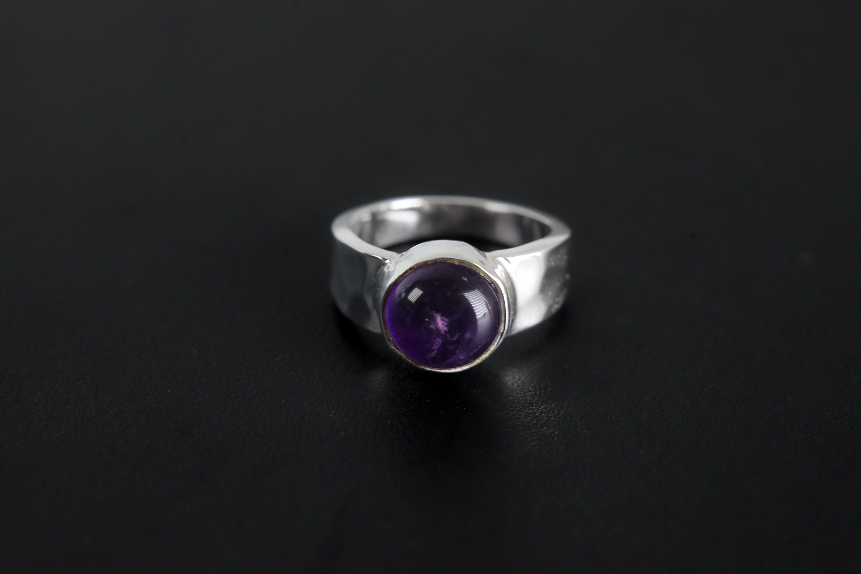 Harmonious Amethyst Essence Ring shown on black background with round purple Amethyst and polished sterling silver band.