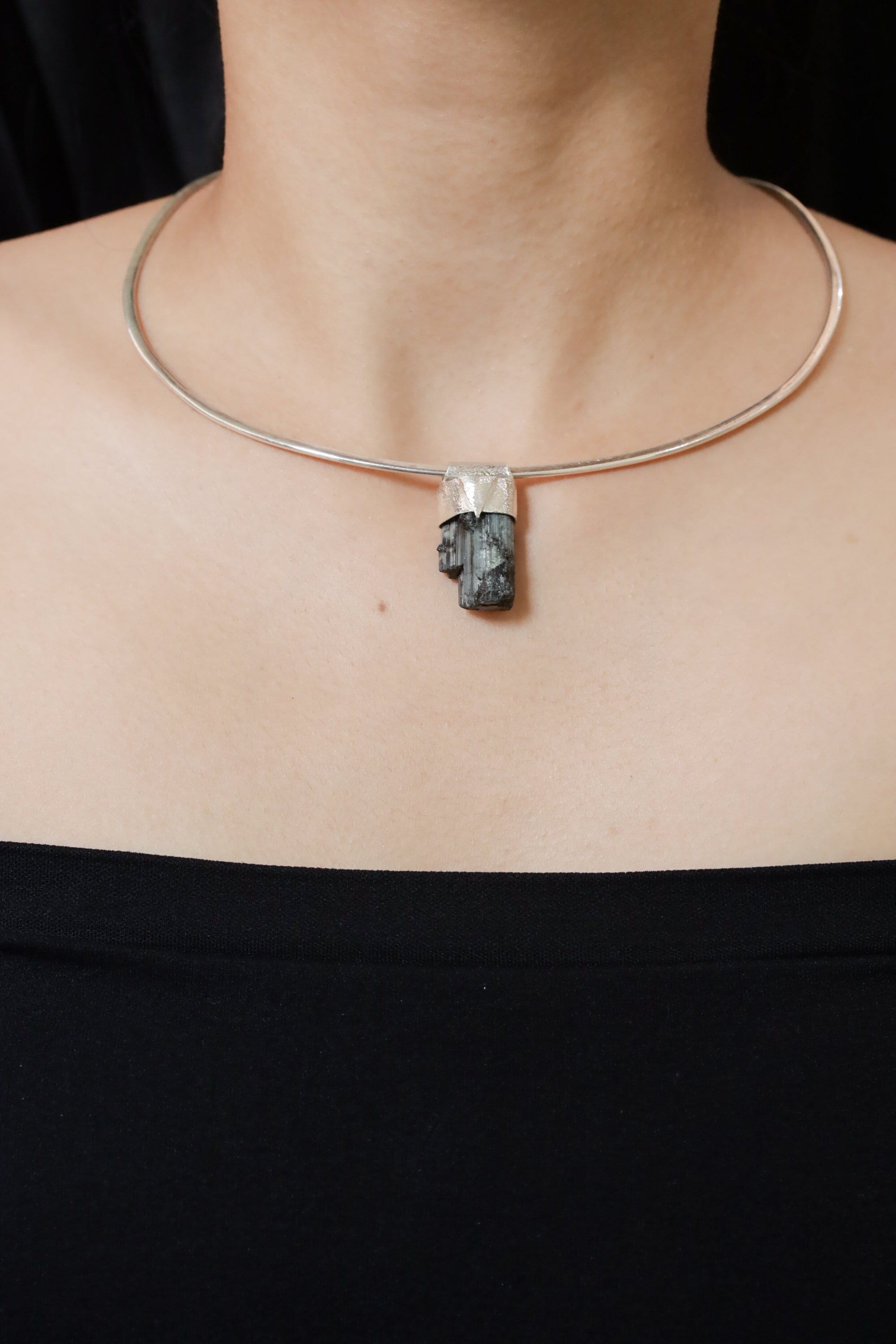 Green Tourmaline Stack Pendant shown worn on the chest with sterling silver cap and raw green crystal.