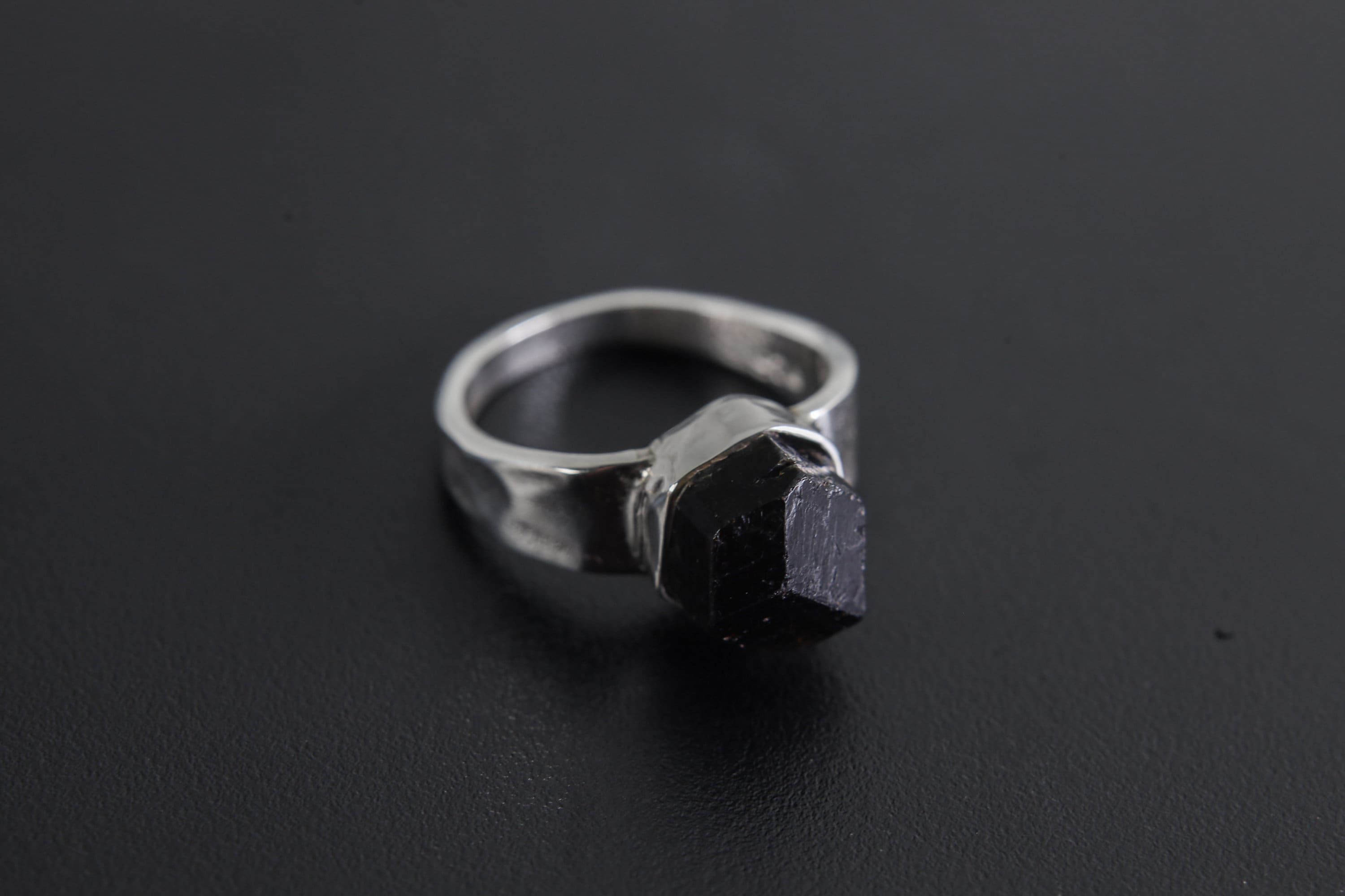 Handmade 925 sterling silver Black Tourmaline ring shown on a dark background, with raw black crystal and hammered silver band.