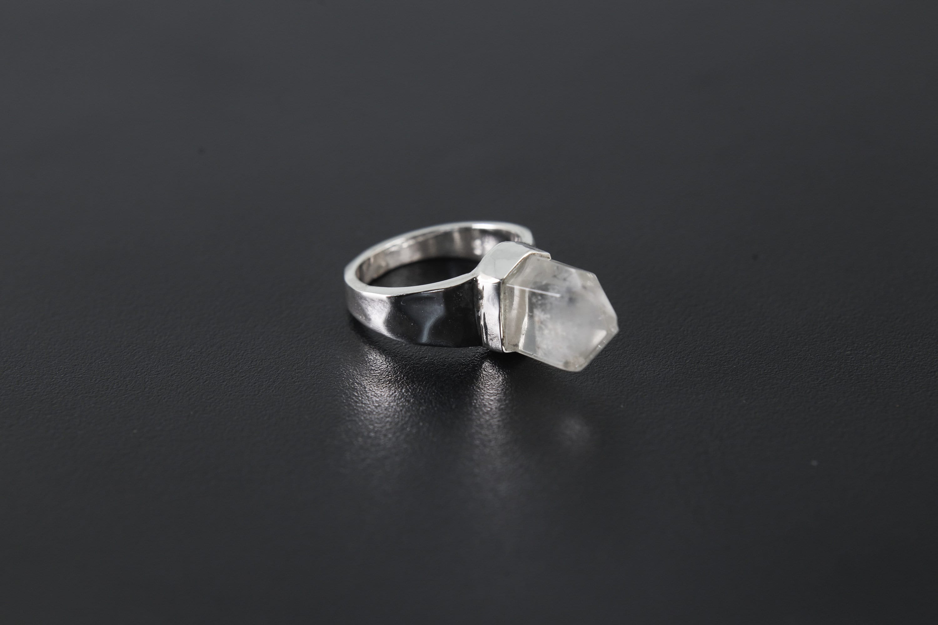 Handmade 925 sterling silver Cacoxenite Quartz point ring shown on a dark background, with clear crystal point and hammered band.