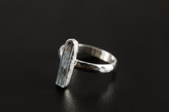 Side view of long square cut Aquamarine ring showing hammered sterling silver band and slim blue gemstone setting.