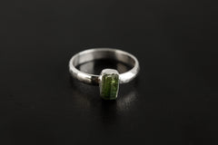 Green Tourmaline hammered silver ring shown on a dark background, with vertical green gemstone and polished 925 sterling silver band.