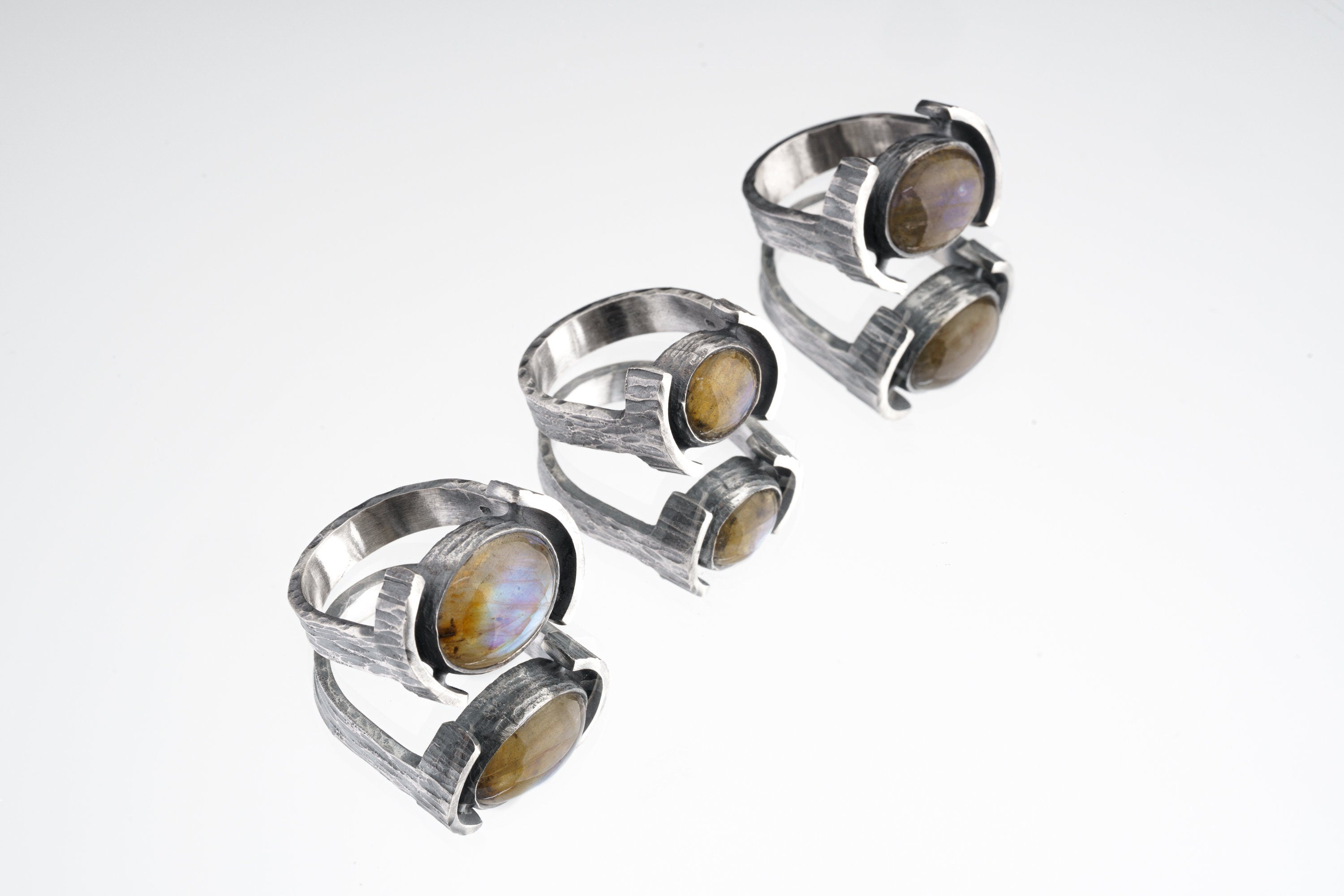 Oval Labradorite Oxidized Silver Ring shown on white background with wide hammered sterling silver band and flashing gemstone.