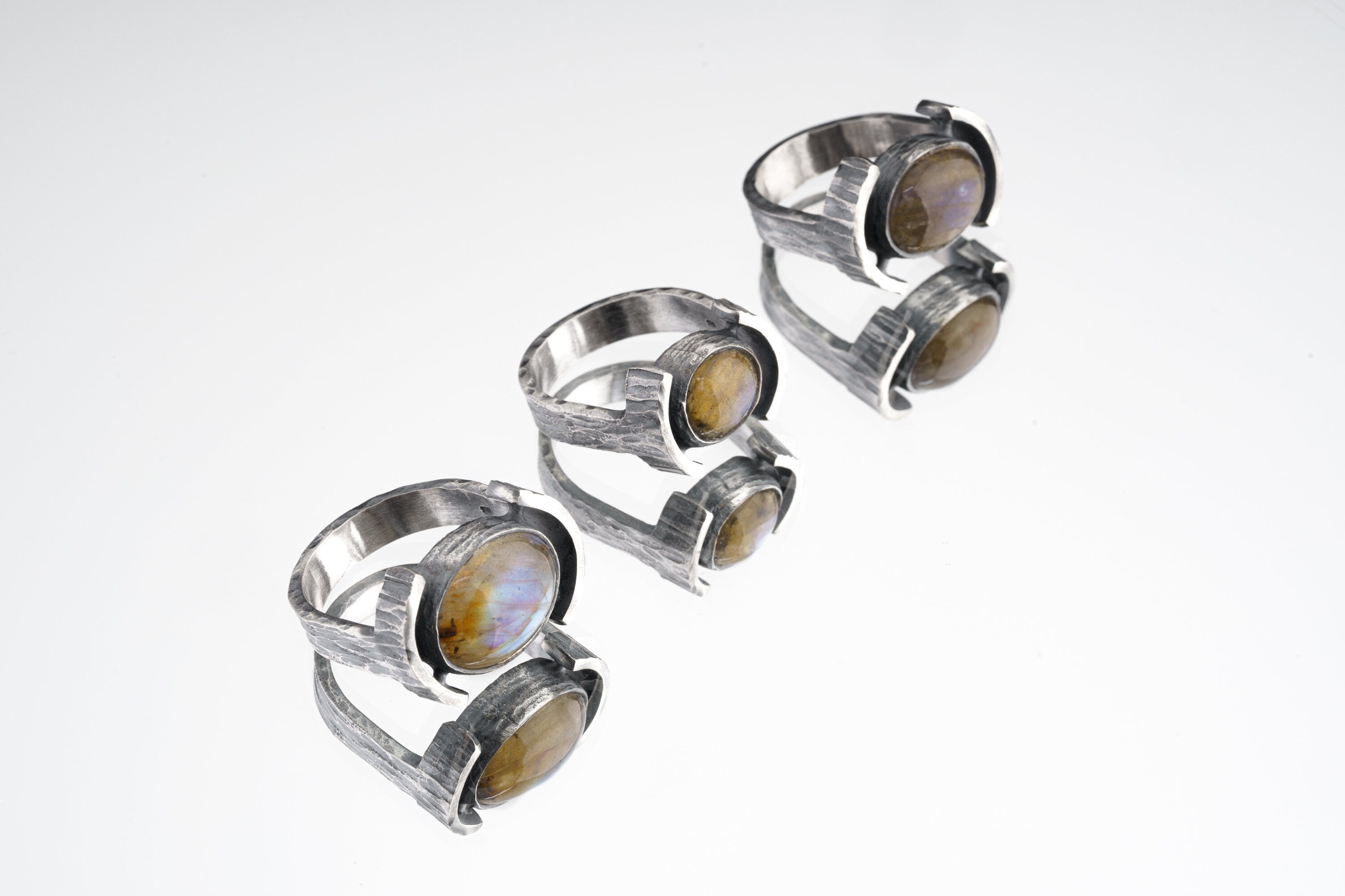 Oval Labradorite Oxidized Silver Ring shown on white background with wide hammered sterling silver band and flashing gemstone.