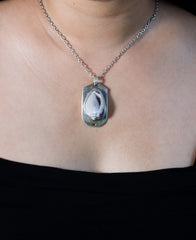 Ancient Tide Drusy Shell pendant worn on chest with polished sterling silver setting and fossil shell centre.