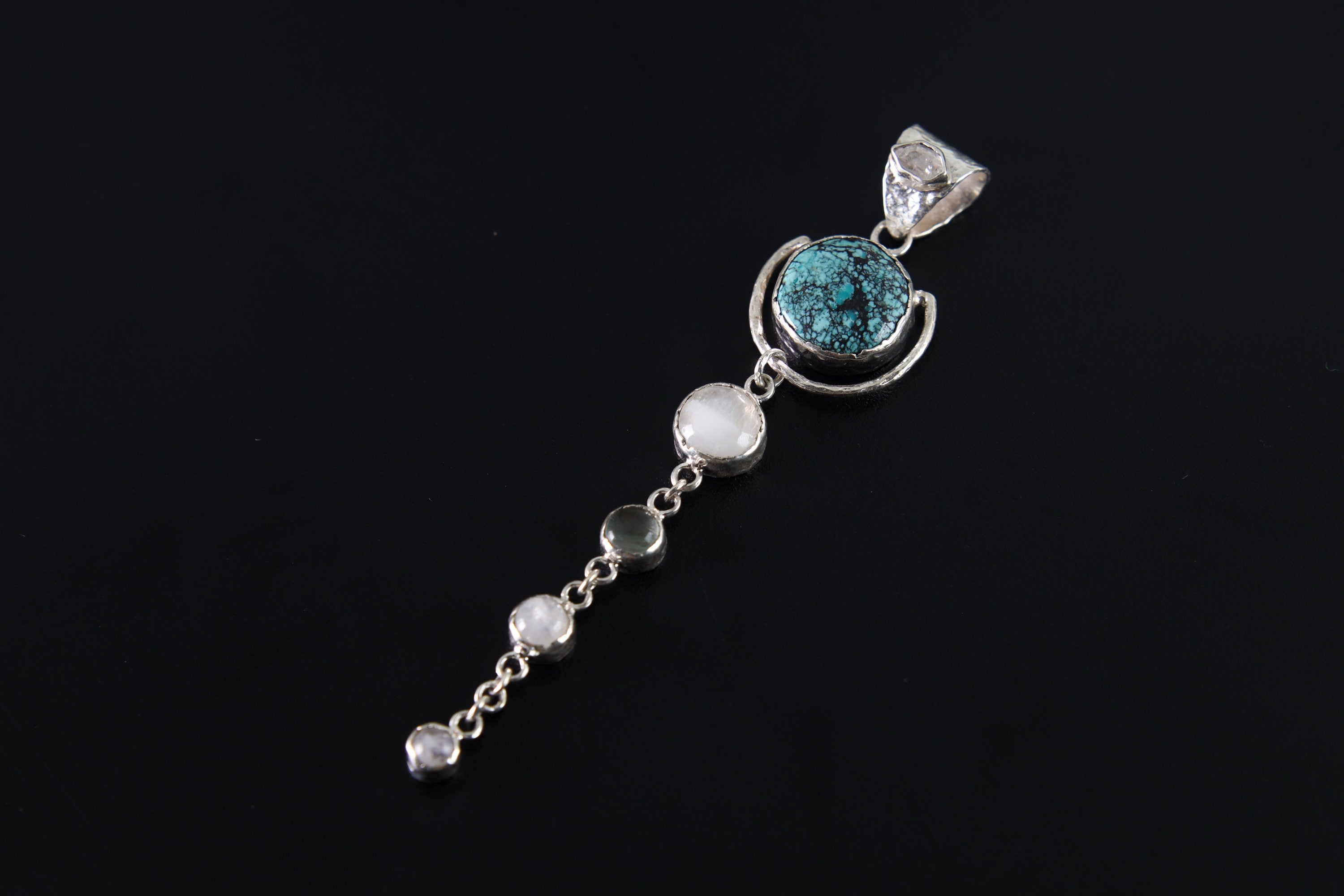 Turquoise Moonstone orbital pendant shown on a dark background, with polished sterling silver and three dangling Moonstones.