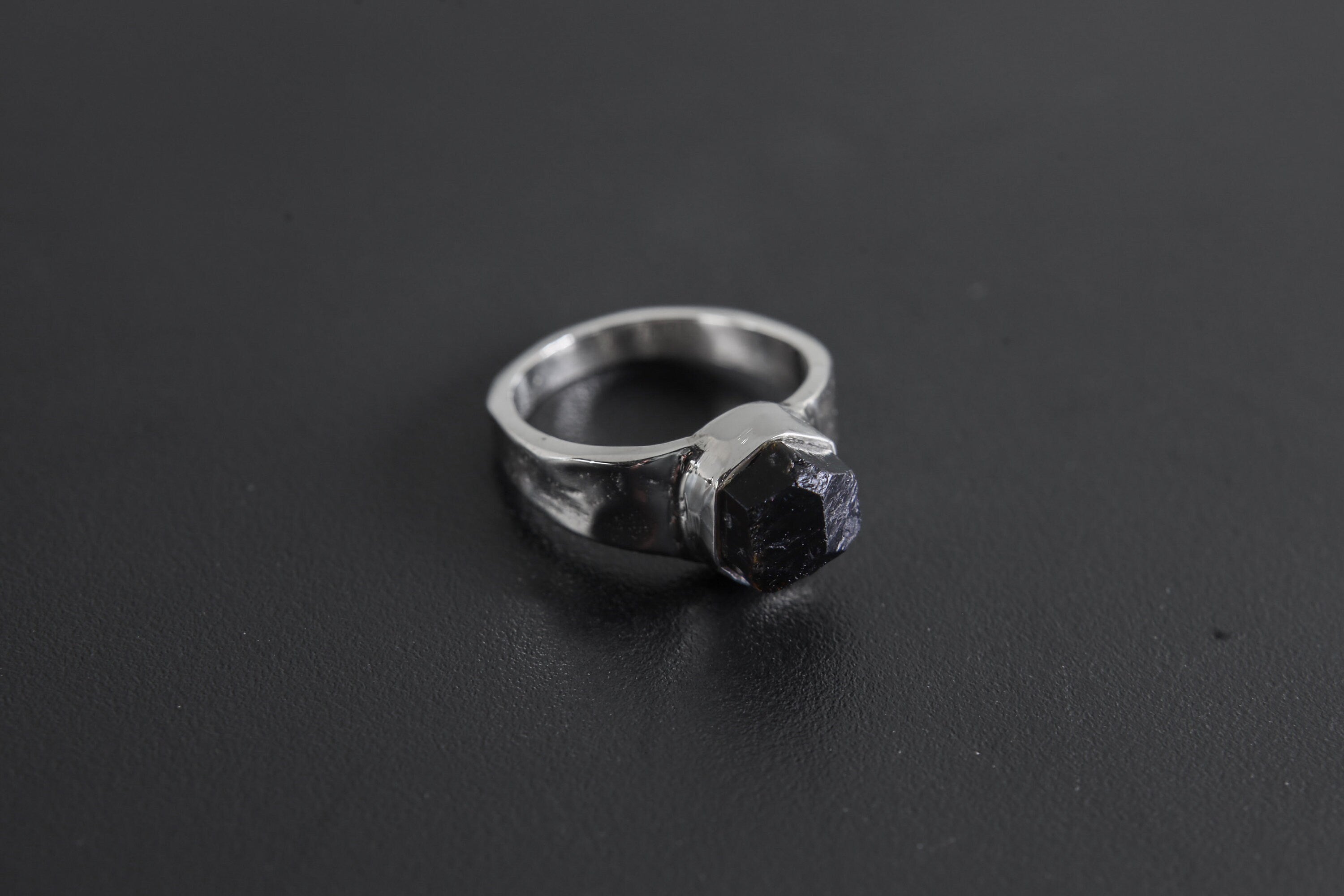 Side view of handmade Black Tourmaline ring showing the raised raw stone, bezel setting, and polished silver band.