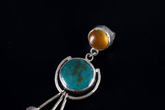 Close-up of round Turquoise orb and Carnelian in a polished sterling silver cosmic pendant setting.