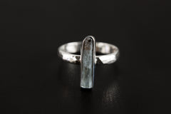Aquamarine silver ring shown on a dark background, with polished 925 sterling silver band and vertical blue stone setting.