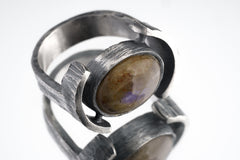 Close-up of Oval Labradorite Oxidized Silver Ring showing blue-green flash and wide hammered sterling silver band.