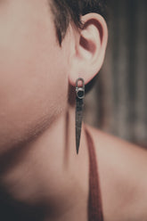 Oxidized Sapphire hammered sterling silver stud earrings shown worn on the ear with long sculptural silver drops.