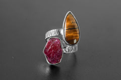 Tiger Eye and Raw Ruby dual-stone ring on a dark background, showing open adjustable band and oxidized silver accents.