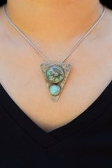 Turquoise triangle pendant worn on necklace with oxidized sterling silver setting.