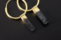 Close-up of Black Tourmaline hoop earrings showing raw striated crystal wands and warm gold-plated silver fittings.