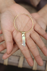Angel Aura Quartz hoop earring pendant held in hand, showing large gold hoop and luminous iridescent crystal.