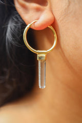Clear Quartz gold-plated hoop earring worn on a model, showing large single crystal dangle styling.