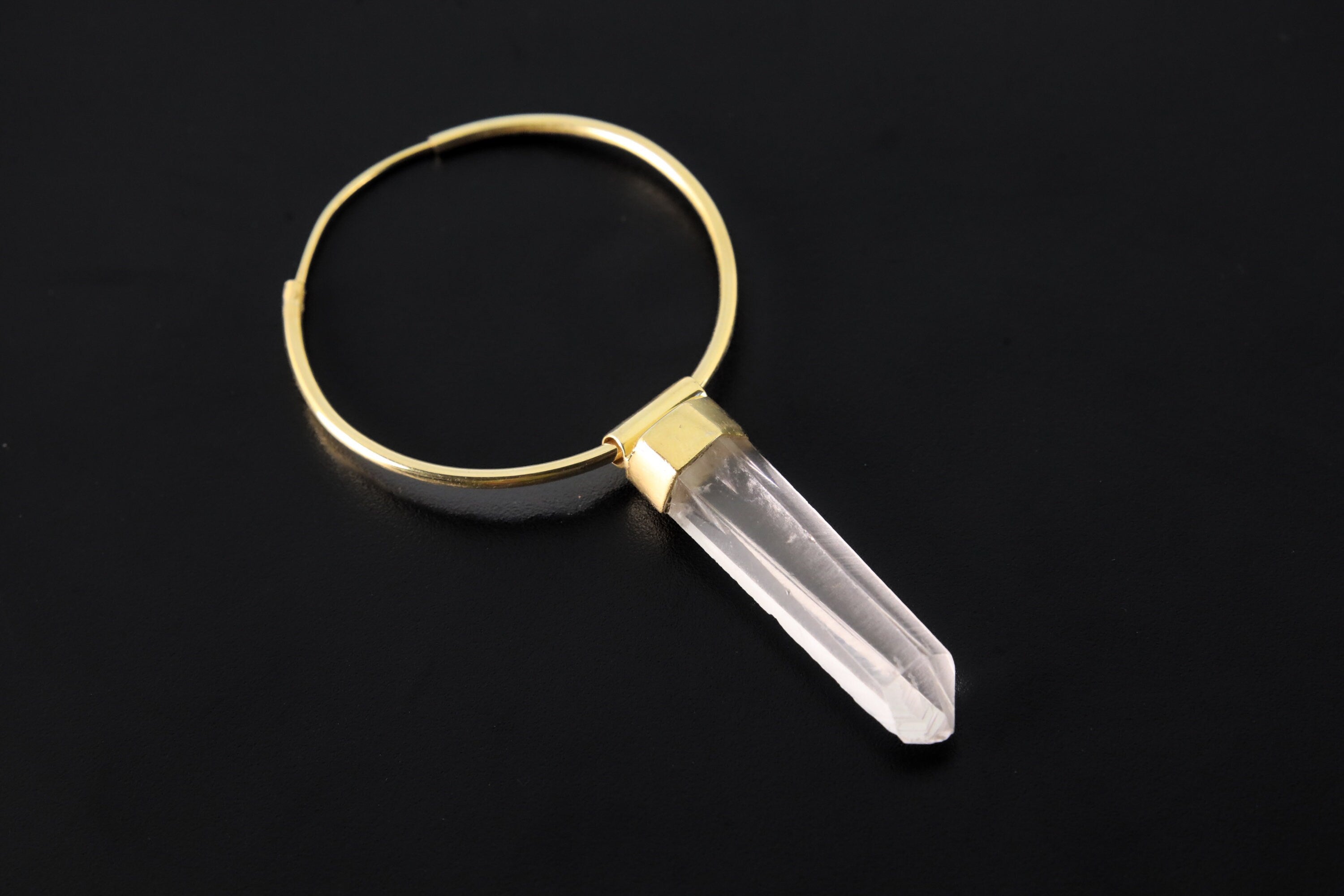 Lemurian Quartz gold-plated sterling silver dangle hoop earring shown on dark background with clear crystal point.