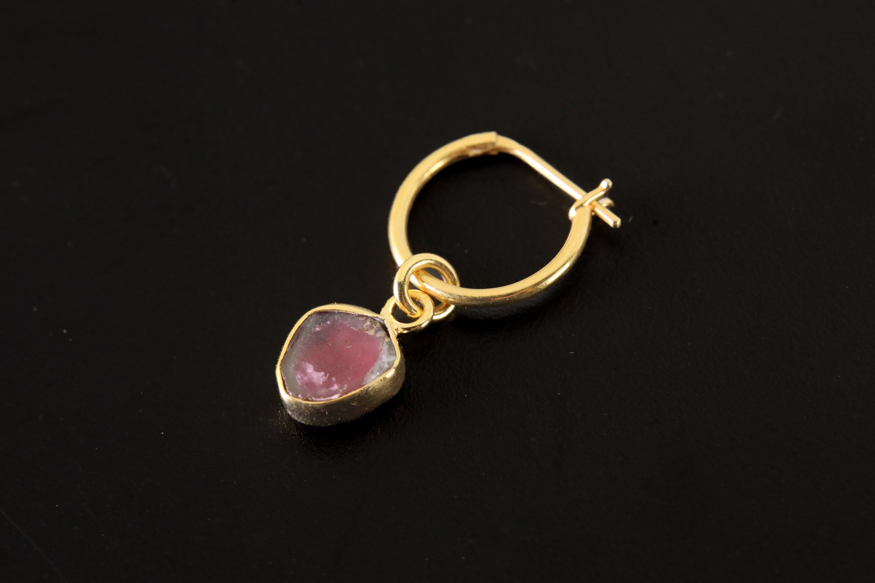 Watermelon Tourmaline gold-plated sterling silver hoop earring shown on dark background with pink green gem slice.