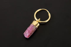 Ruby hoop earring pendant shown on dark background with polished gold-plated hoop and raw red gemstone.