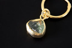 Close-up of Green Tourmaline hoop earring pendant showing Verdelite slice and polished gold-plated setting.
