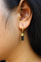 Black Tourmaline hoop earrings shown worn on the ear, with gold-plated sterling silver hoops and raw crystal wands.