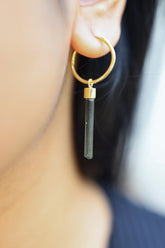 Green Tourmaline gold-plated sterling silver dangle hook earring worn on a model as a single crystal charm.