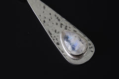 Close-up of Blue Moonstone teardrop pendant showing luminous gemstone glow and hammered silver texture.