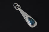Rhodochrosite teardrop pendant shown on dark background with hammered sterling silver and pink gemstone centre.