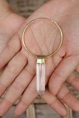 Lemurian Quartz dangle hoop earring held in hand, showing clear crystal point and gold-plated silver cap.