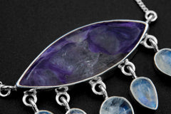 Close-up of AAA-grade eye-shaped Charoite in an open-back sterling silver bezel with purple swirls and hammered texture.