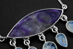 Close-up of AAA-grade eye-shaped Charoite in an open-back sterling silver bezel with purple swirls and hammered texture.