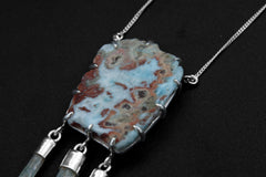 Close-up of raw polished Larimar slice held by 12 sterling silver prongs, with blue Aquamarine stick dangles below.