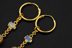 Ethiopian Opal Pearl hoop earrings shown on a dark background with gold-plated hoops and luminous Pearl drops.