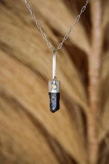 Blue Apatite Ethiopian Opal pendant shown hanging against natural grass texture, with silver chain and vivid blue crystal point.