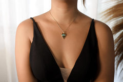 Pentagonal Turquoise pendant shown worn on a necklace, with 18k gold-plated sterling silver setting and geometric blue stone.