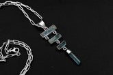 Raw Aquamarine cascade pendant in 925 sterling silver with four blue stones, open-back bezels, and a black necklace cord.