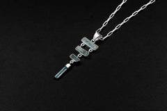 Sterling silver Aquamarine cascade pendant shown on a dark background, with four raw blue stones arranged in a flowing vertical design.