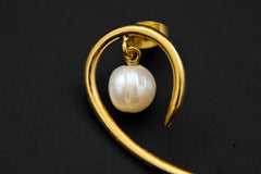 Close-up of Heritage Pearl curled horn earring showing 18k gold-plated silver curve and luminous Pearl centre.