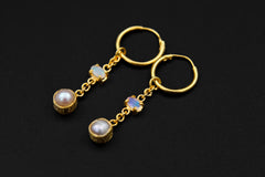 Ethiopian Opal Pearl hoop earrings shown on a dark background with gold-plated hoops and luminous Pearl drops.