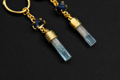 Close-up of Sapphire and Aquamarine gold-plated hoop earrings showing textured silver detail and blue stones.
