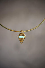Small pentagonal Turquoise pendant shown on a gold-toned necklace, with double bail setting and compact geometric shape.