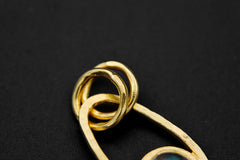 Close-up of gold-plated Sun and Moon pendant showing round Rainbow Labradorite cabochon and textured celestial frame.