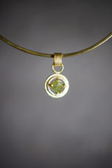 Raw AAA Grade Peridot claw pendant in 18k gold-plated sterling silver, shown on a black background with vivid green stone.