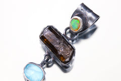 Close-up of Opal, Dravite Tourmaline, Aquamarine, and Turquoise in a hand-hammered oxidized sterling silver pendant.