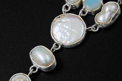 Close-up of South Sea Pearls and Faceted Opal in a sterling silver linked necklace with brushed bezel texture.
