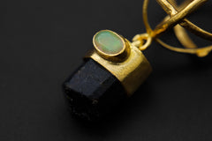 Close-up of Ethiopian Fiery Rainbow Opal set into a gold-plated cap above Himalayan Brown Tourmaline.